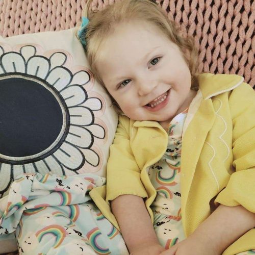 Girl in yellow coat sitting by sunflower pillow